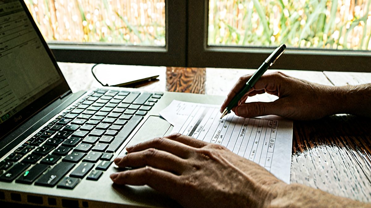 Młoda przedsiębiorczyni sprawdza na ekranie laptopa podgląd pierwszej faktury, obok notes i telefon